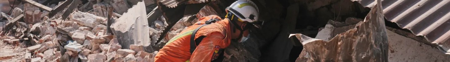 Emergency responder digs through rubble from earthquake.