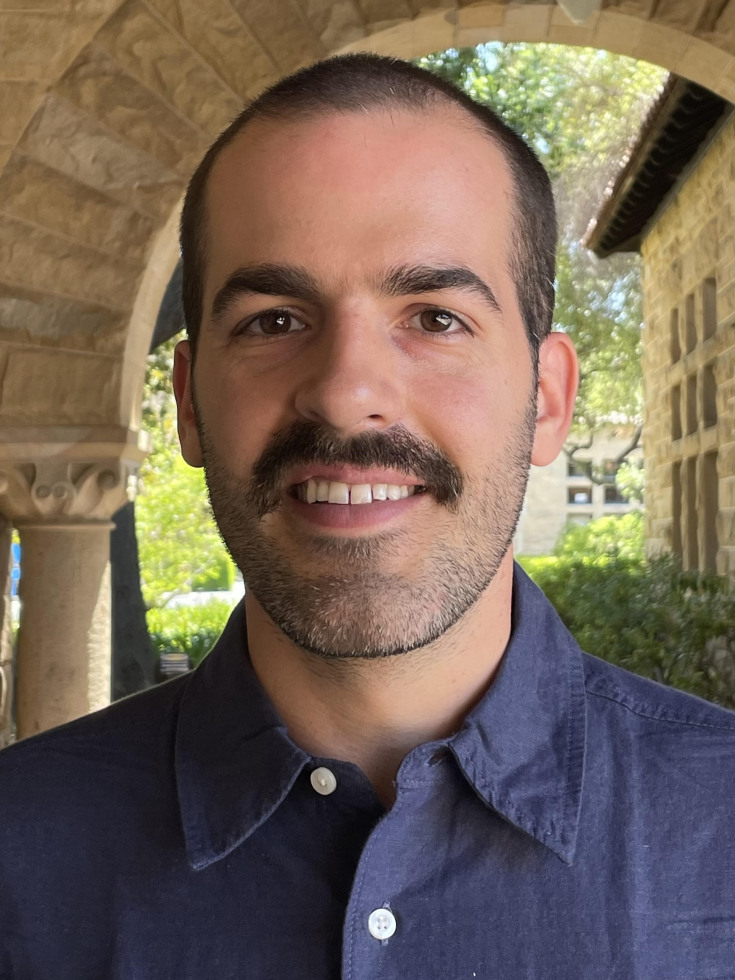 Man with dark hair smiling. 