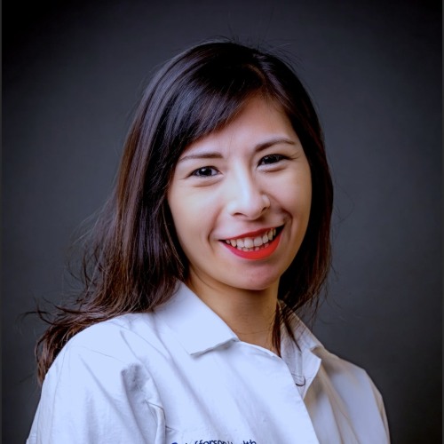 Brunette woman smiling with white coat on.