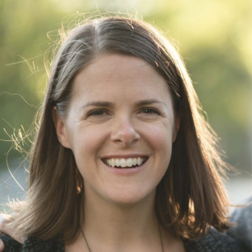 Woman with short brown hair smiling in the sunshine.