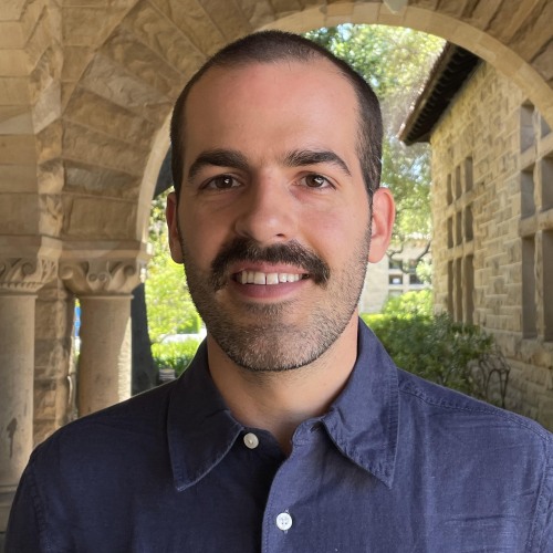 Man in blue collared shirt smiling. 