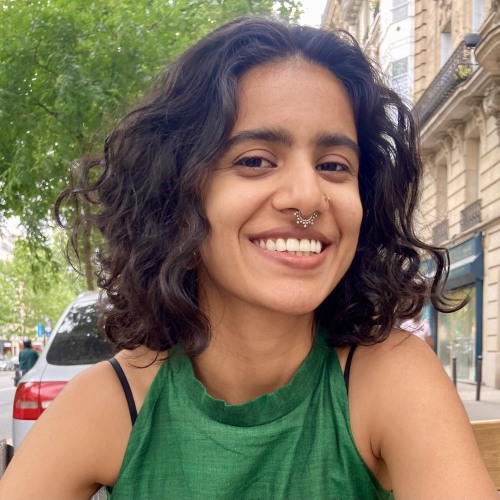 woman with short brown curly hair smiling, wearing green top.