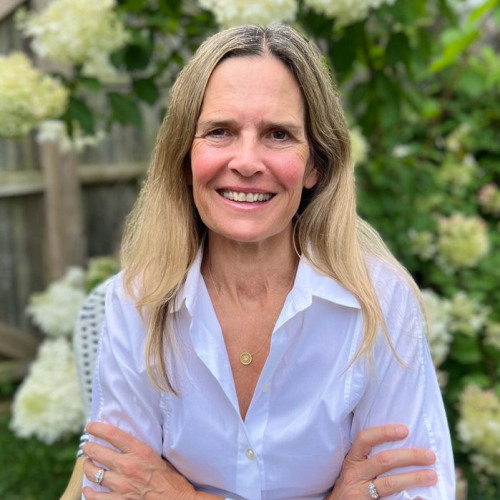 Woman with blonde hair smiling with her arms crossed. 