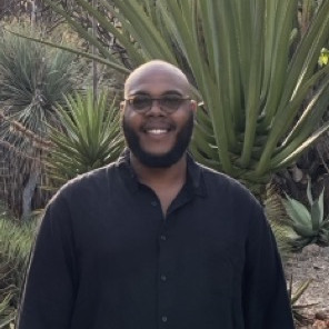 Man with beard wearing black button down shirt smiling.